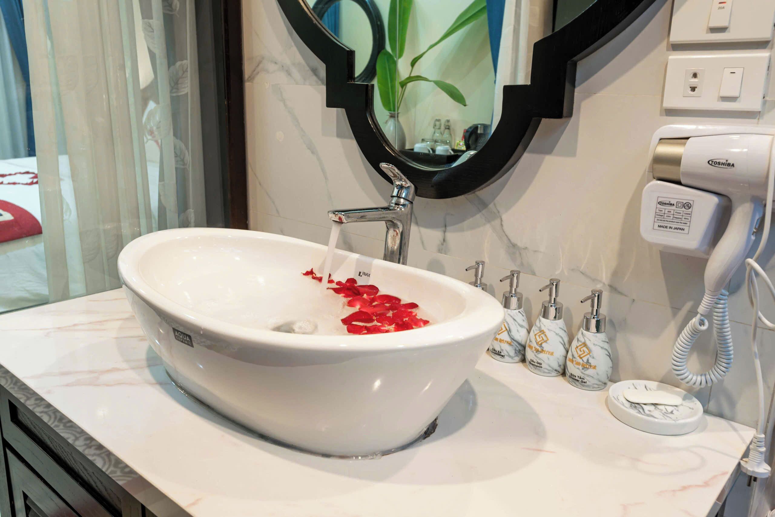 A bathroom with a white sink, a mirror, a towel, and a hand dryer.