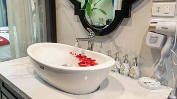 A bathroom with a white sink, a mirror, a towel, and a hand dryer.