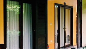 A yellow building with a covered porch, a wooden bench, and a door with a black frame. - Luong Son Retreat (Luong Son)