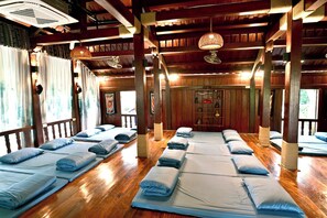A room with multiple beds arranged in rows, wooden floors, and a traditional ceiling design. - Luong Son Retreat (Luong Son)