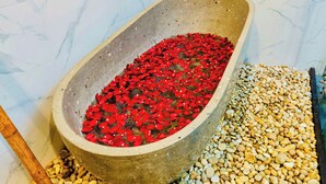 A bathtub filled with red rose petals and surrounded by pebbles. - Luong Son Retreat (Luong Son)