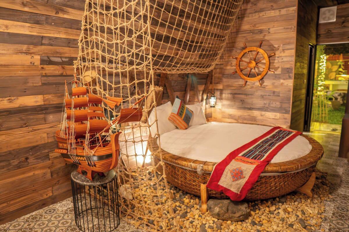 Una habitación acogedora con una cama, un modelo de barco y una pared de madera.