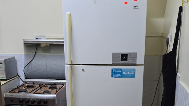 Una cocina compacta con un refrigerador blanco, una estufa a gas y un microondas.