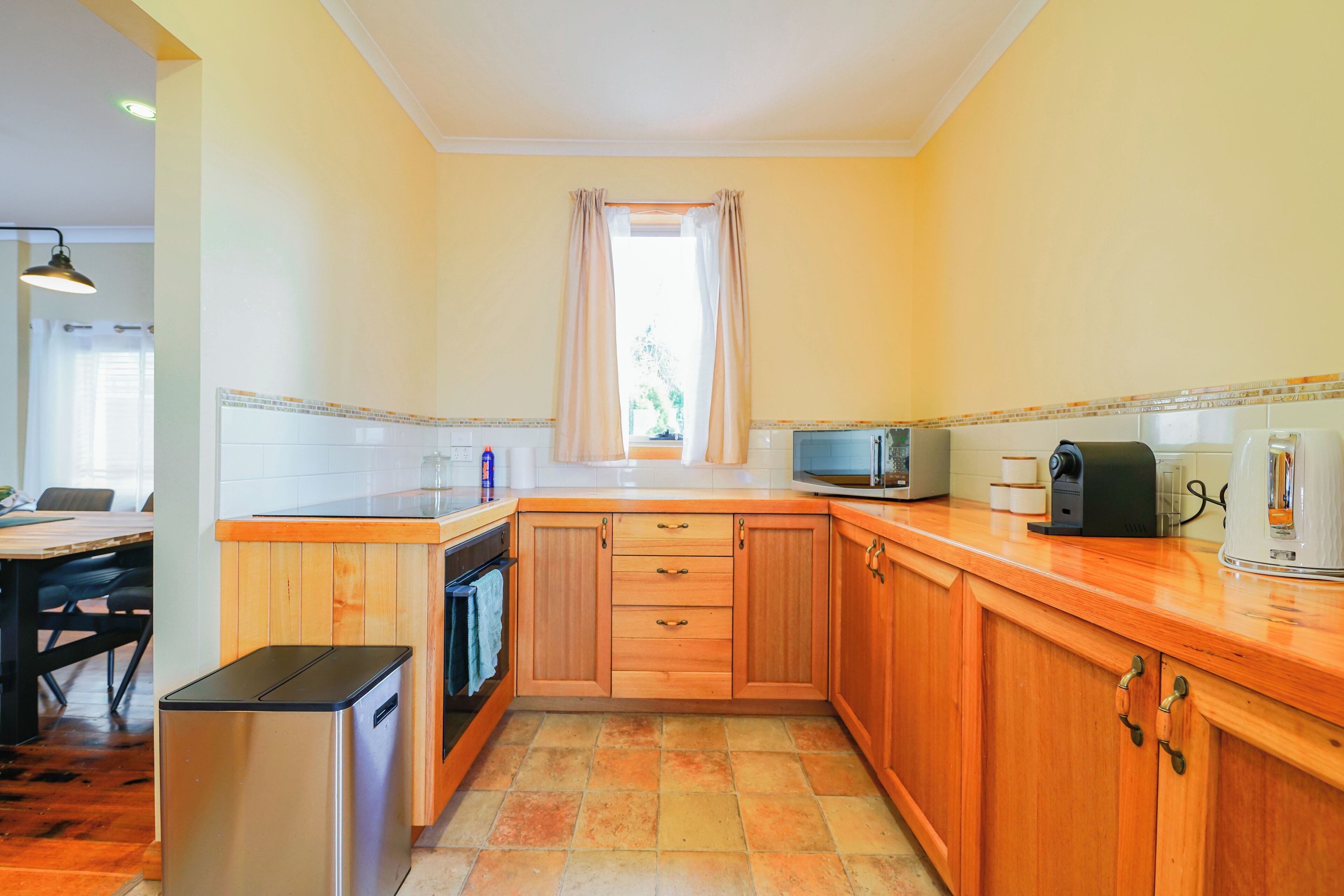A compact kitchen with wooden cabinets, a microwave, a coffee maker, and a small refrigerator.