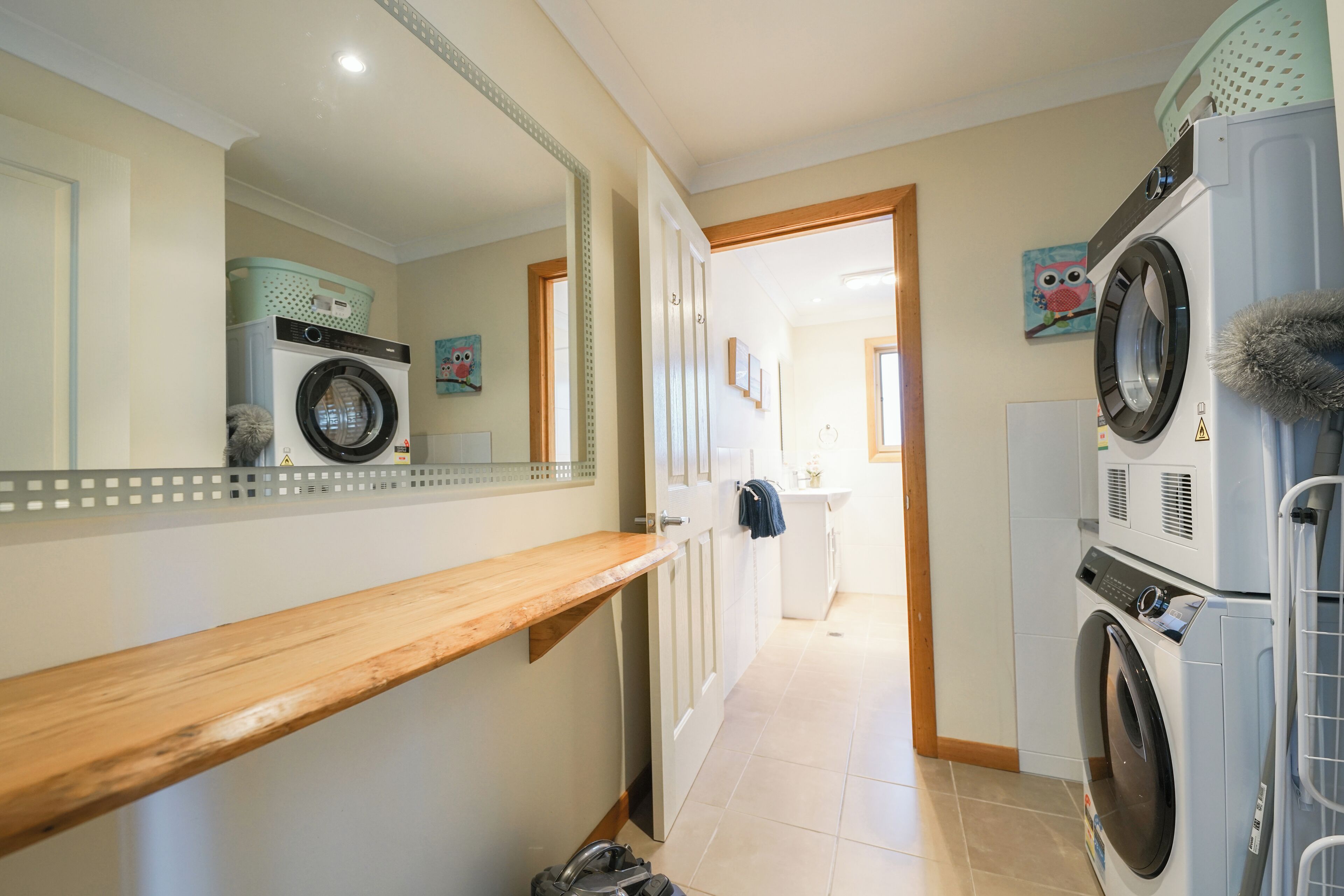 Une buanderie équipée de deux machines à laver, d’un sèche-linge et d’une étagère en bois.