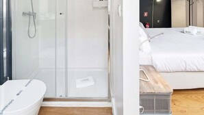 Un bagno moderno con cabina doccia in vetro, una vasca da bagno bianca e un pavimento in legno.