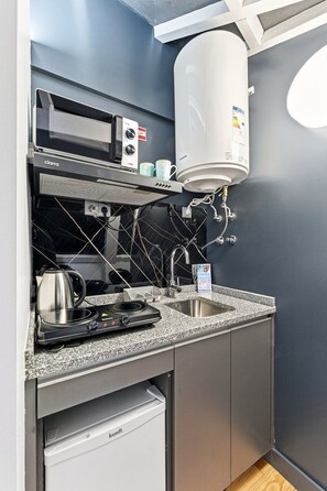 Une petite cuisine équipée comprenant une cuisinière intégrée, une machine à café et un chauffe-eau.