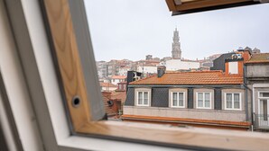 Une vue depuis une fenêtre donnant sur un paysage urbain, avec une tour imposante en arrière-plan.