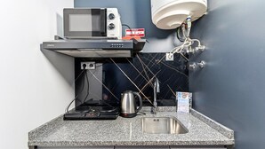 Une petite cuisine équipée d’un four à micro-ondes, d’une machine à café et d’un évier.