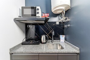 Une petite cuisine équipée d’un four à micro-ondes, d’une machine à café et d’un évier.