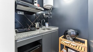 Een kleine keuken met een magnetron, waterkoker, spoelbak en koffieapparaat.