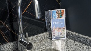 Een brochure met de titel 'Embrace Porto' ligt op een granieten aanrecht in de buurt van een gootsteen met een kraan.