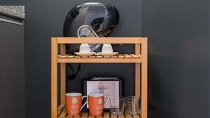 Een keuken met een houten wandplank vol servies, kopjes en een koffiezetapparaat.