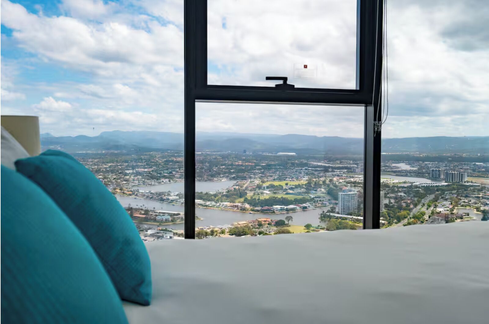 A bedroom with a large window overlooking a cityscape and a river.