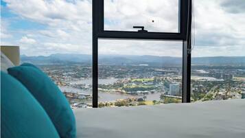 A bedroom with a large window overlooking a cityscape and a river.