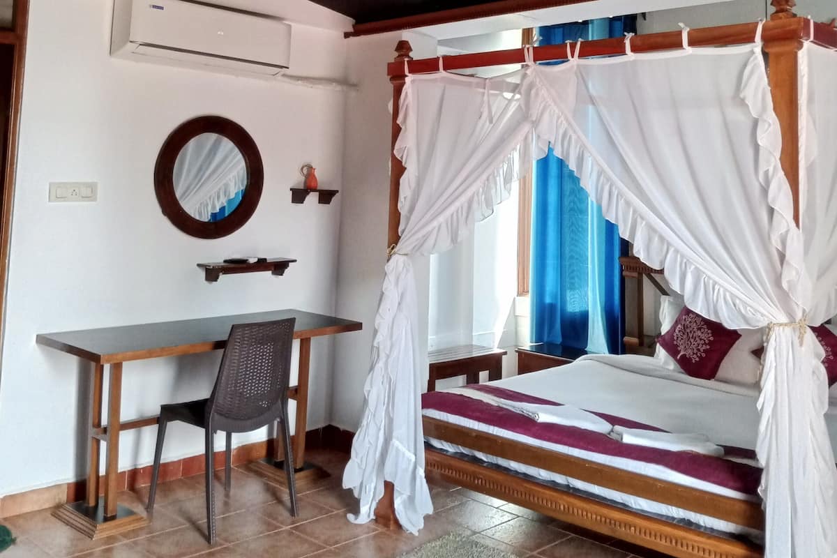 Un dormitorio con una cama con dosel, un escritorio, una silla y un ventilador de techo.
