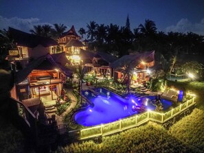 Ein Resort mit mehreren Gebäuden, einem Swimmingpool und üppiger Bepflanzung.