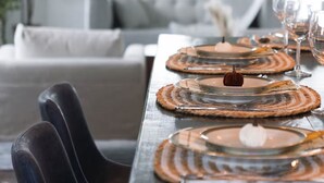 A dining table set with placemats, plates, and glasses, with a clock on the wall in the background. - Luxury family retreat on lakefront with breathtaking view, game room, gym &more! (Kawartha Lakes)
