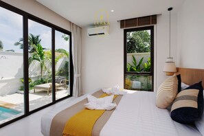 A hotel room with a large bed, a view of a swimming pool, and a window overlooking greenery. - Elegant 3-Bedroom Private Pool Villa, Perfect for Long Stays (Tambon Rawai)