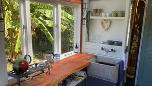 Een kleine keuken met een houten aanrecht, een spoelbak en een raam met uitzicht op groen.