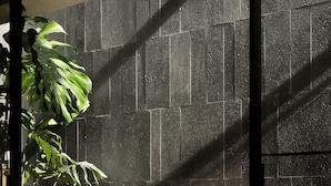 A modern outdoor seating area with a table and two wooden chairs, a potted plant, and a textured wall in the background. - AnHeANAHATA (Datong)