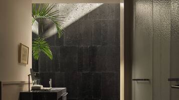 A modern bathroom with a large mirror, a sink, and a plant.