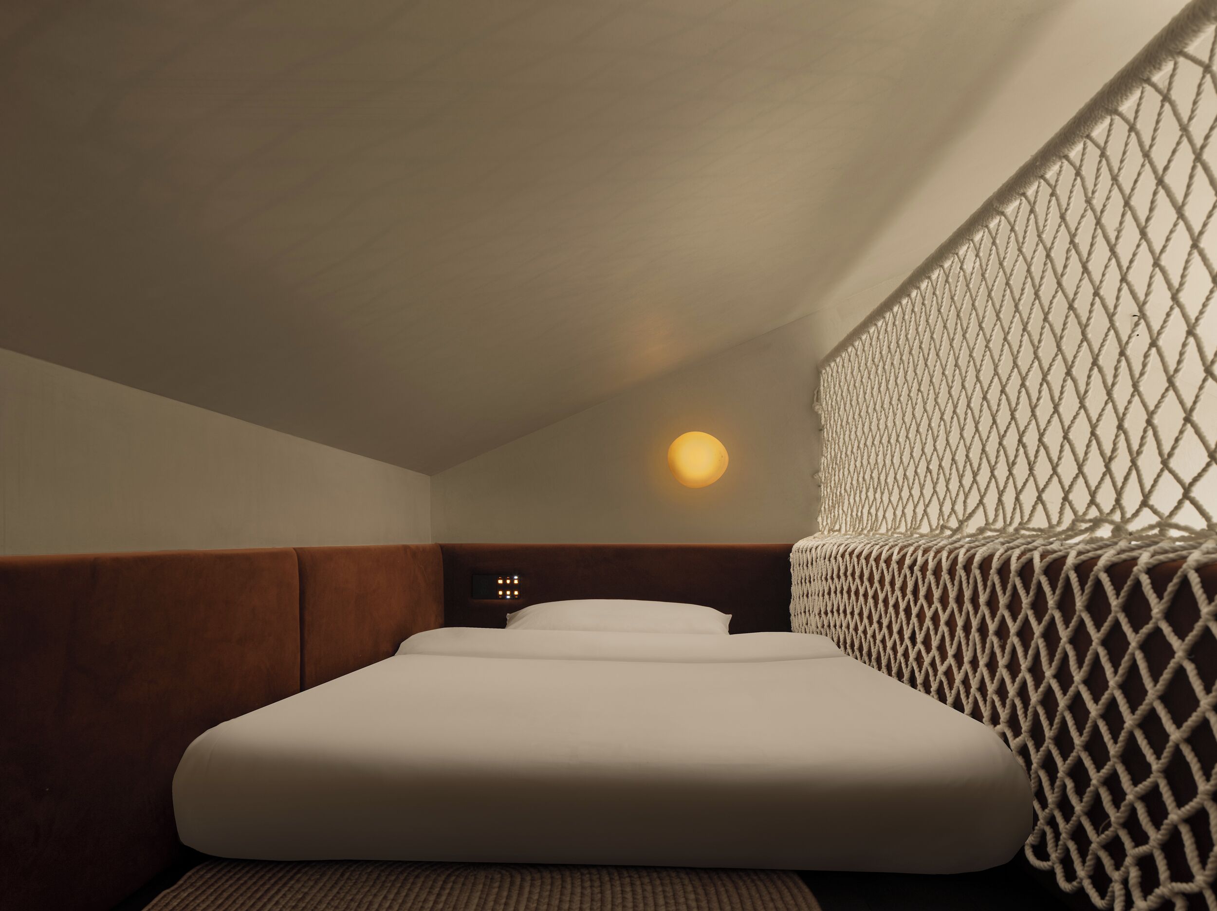 Una habitación de hotel moderna con una cama grande, un cabecero con un diseño geométrico y una lámpara de pared.