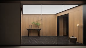 A modern interior with a wooden panel wall, a black tiled floor, a small table with a plant, and a vase. - AnHeANAHATA (Datong)