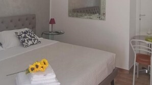 Un dormitorio con cama, un candelabro, un espejo y una mesita de noche con lámpara.