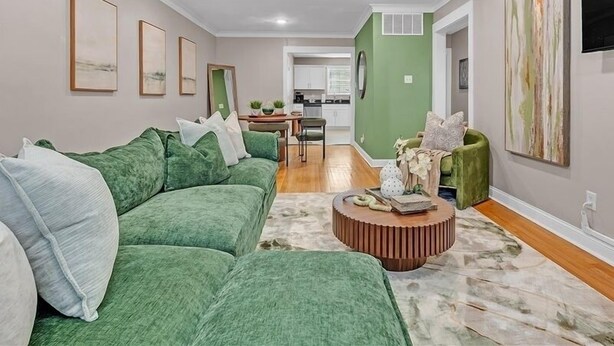 A living room with a green sofa, a coffee table, and a dining area with a kitchen in the background. - Olive Midtown Retreat Walkable, Stylish & Central (Memphis)