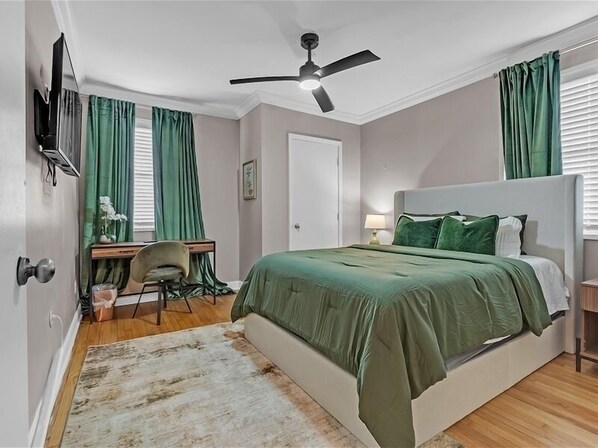 Une chambre à coucher comprenant un lit, un bureau, une chaise et un ventilateur de plafond.