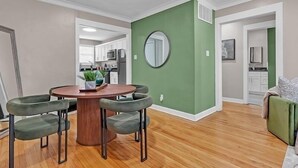 A modern living room with a dining area, green accent wall, and hardwood flooring. - Olive Midtown Retreat Walkable, Stylish & Central (Memphis)