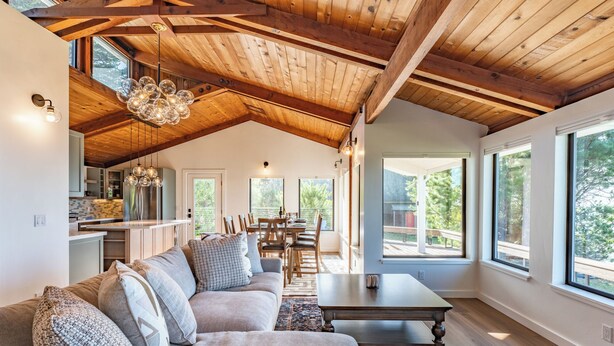 A spacious living area with a high ceiling, wooden beams, a large sofa, and a dining table. - Pacific Seascape - An ocean front gem on the Mendocino coast! (Albion)