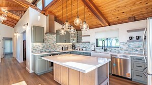 A spacious kitchen with a large island, wooden ceiling beams, and modern appliances. - Pacific Seascape - An ocean front gem on the Mendocino coast! (Albion)