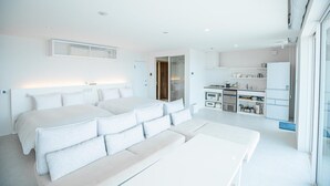 Una habitación de hotel moderna con una cama grande, un sofá, una mesa de comedor y una kitchenette.