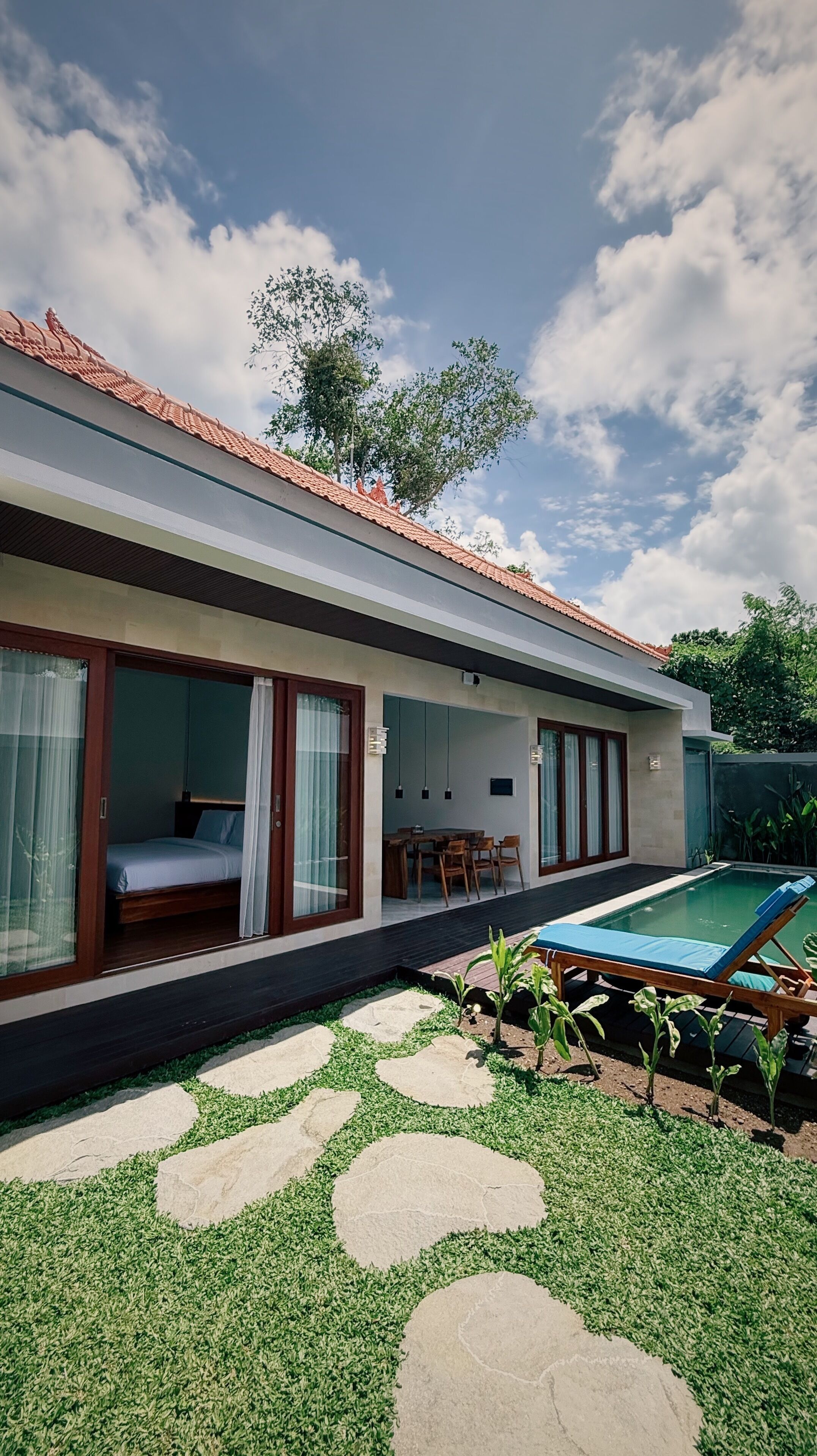 Una casa moderna con piscina, zona pranzo e camera da letto con un'ampia finestra.