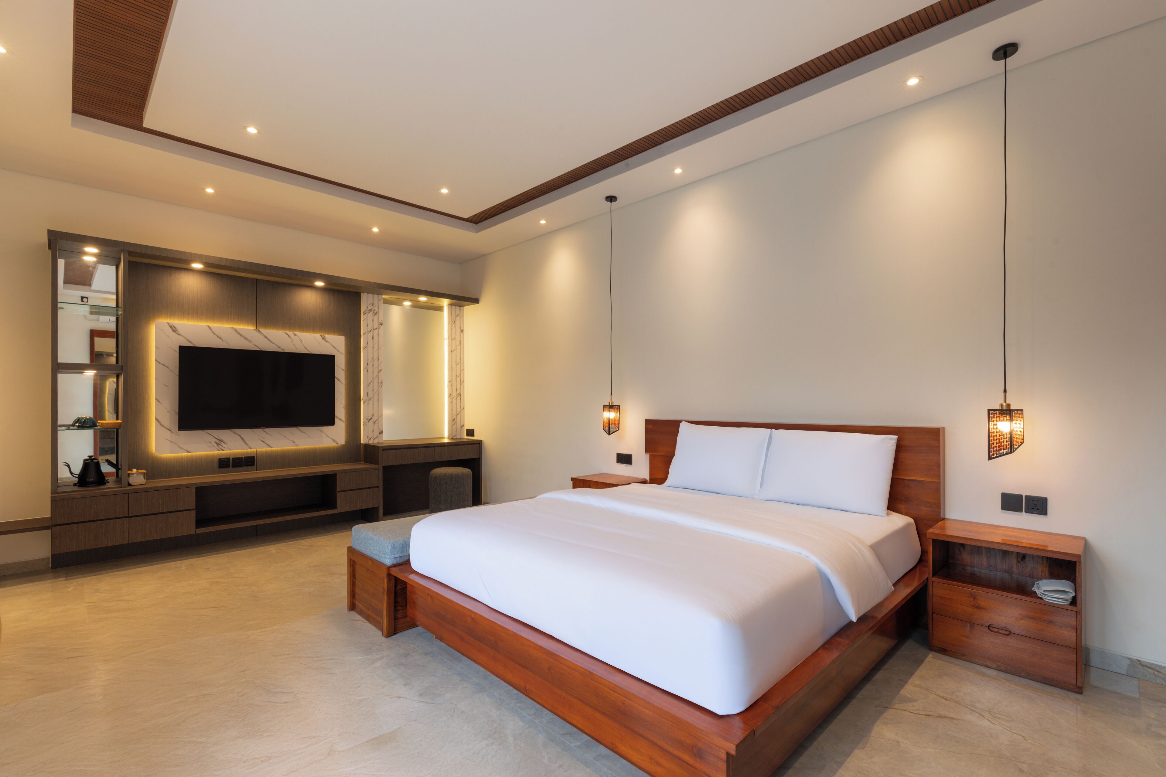 A modern bedroom with a large bed, built-in TV, and a wooden nightstand.
