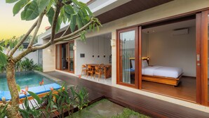 Eine moderne Villa mit Swimmingpool, Holzterrasse und einem Schlafzimmer mit Bett und Schreibtisch.