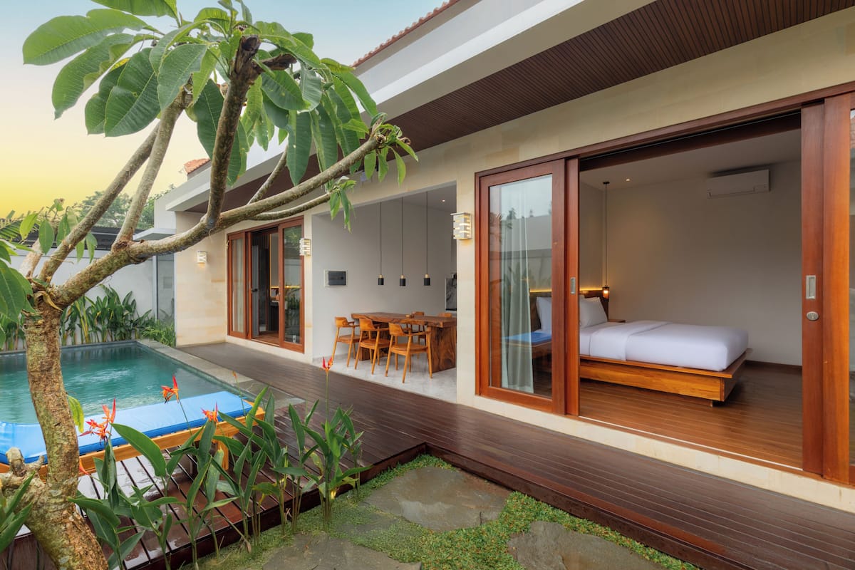A modern villa with a swimming pool, wooden deck, and a bedroom with a bed and a desk.