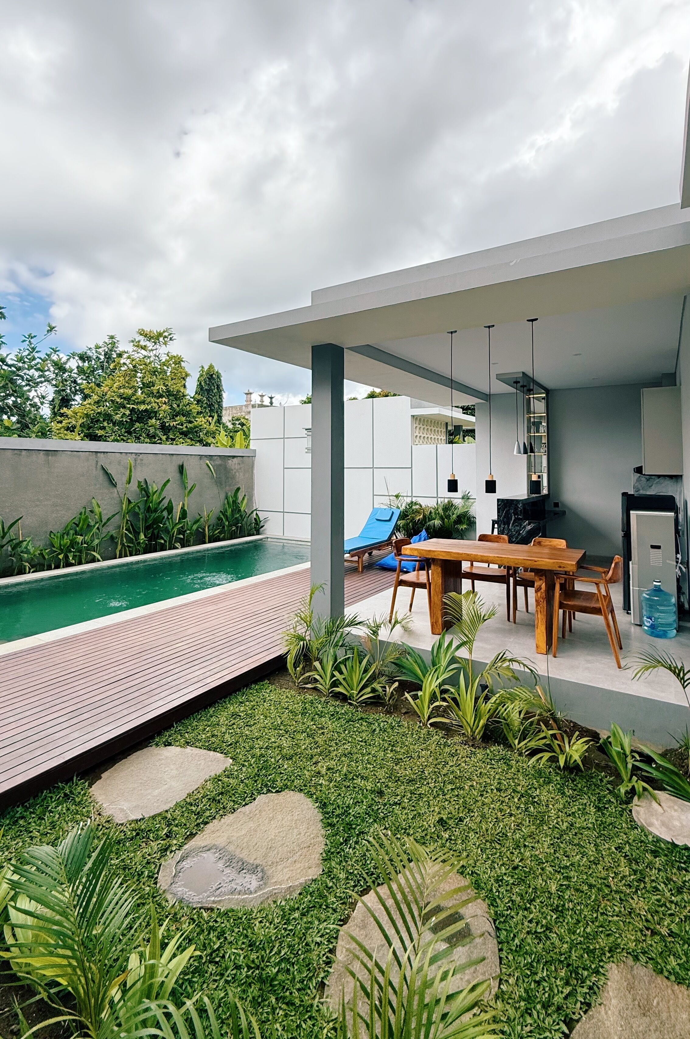 A modern outdoor patio with a pool, dining area, and lounge chairs.
