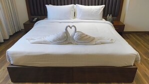 A neatly made bed with white linens and two swan-shaped towels on the bed. - Hotel KRB Greens  (Bahadurgarh)