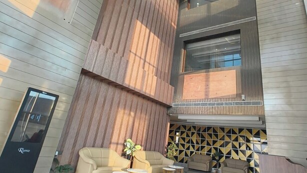 A spacious lobby with a modern chandelier, a reception desk, and a seating area with a patterned floor. - Hotel KRB Greens  (Bahadurgarh)