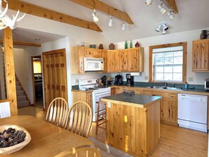 Une cuisine en bois dotée d’un îlot central, de meubles de rangement en bois, d’une cuisinière et d’un lave-vaisselle.