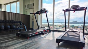 Ein Fitnessraum mit Laufbändern, einem Rudergerät und einer Sammlung von Kurzhanteln.