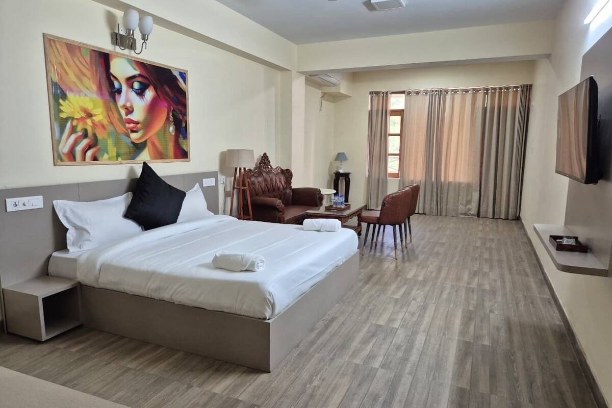 A hotel room with a large bed, a desk, a chair, and a TV.