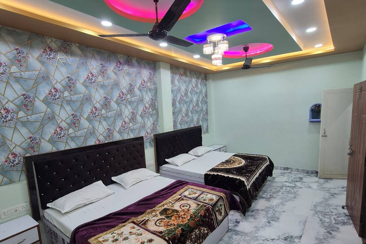 A bedroom with two beds, a ceiling fan, and a decorative light fixture.