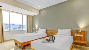Hotellihuone, jossa on kaksi sänkyä, näköala sillalle ja ikkuna, jossa on verhot.
