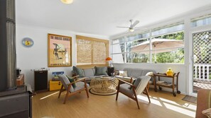 A sunlit living room with a sofa, chairs, a coffee table, and a bookshelf. - Budawang near Green Island (Cunjurong Point)
