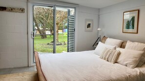 A bedroom with a bed, a window, and a door leading to an outdoor area. - Budawang near Green Island (Cunjurong Point)