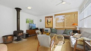 Ein Wohnzimmer mit Kamin, Fernseher, Sofa und einem Fenster mit Jalousien.